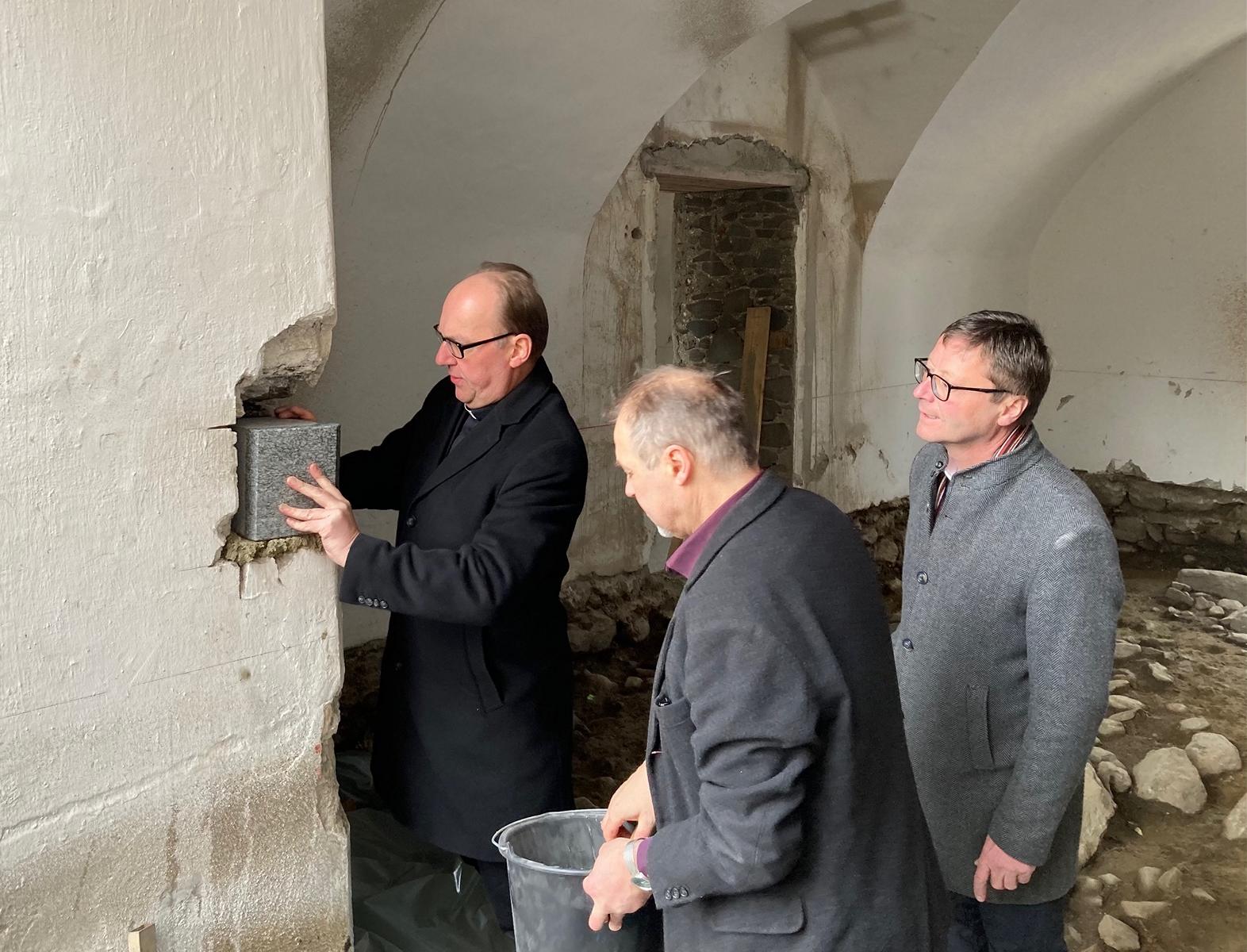 Bischof Hermann Glettler mit Architekt Paul Senfter und Dekan Franz Troyer beim Einmauern des Grundsteins. Foto: Stangl
