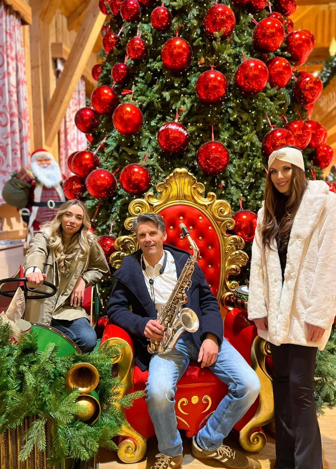Judith und Sara zusammen mit Wolfram Dullnig von der Band "Saxolution" vor dem wunderschön geschmückten Christbaum auf Gut Aiderbichl.
