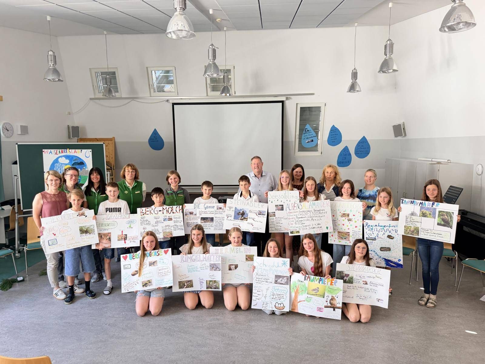 Die Forscher*innen der 1a Klasse der nationalparkmittelschule Defereggental bei der Abschlusspr&auml;sentation des Projektes mit den Ehreng&auml;sten hinten v.l. Clusterleiter-Stellvertreter Doris Jesacher, den Verantwortlichen vom Nationalpark Hohe Tauern &ndash; Brigitte Eckle, Carola Trojer, Ruth Bstieler, die Projektleiterin von der Swarovski Foundation Wasserschule Christiane F&uuml;hrer, Clusterleiter Markus T&ouml;nig, Klassenvorst&auml;ndin Marlies Ladst&auml;tter, Clusterbeauftragte der Bildungsdirektion Tirol Claudia Gri&szlig;mann und Lehrerin Viktoria Wurnitsch.