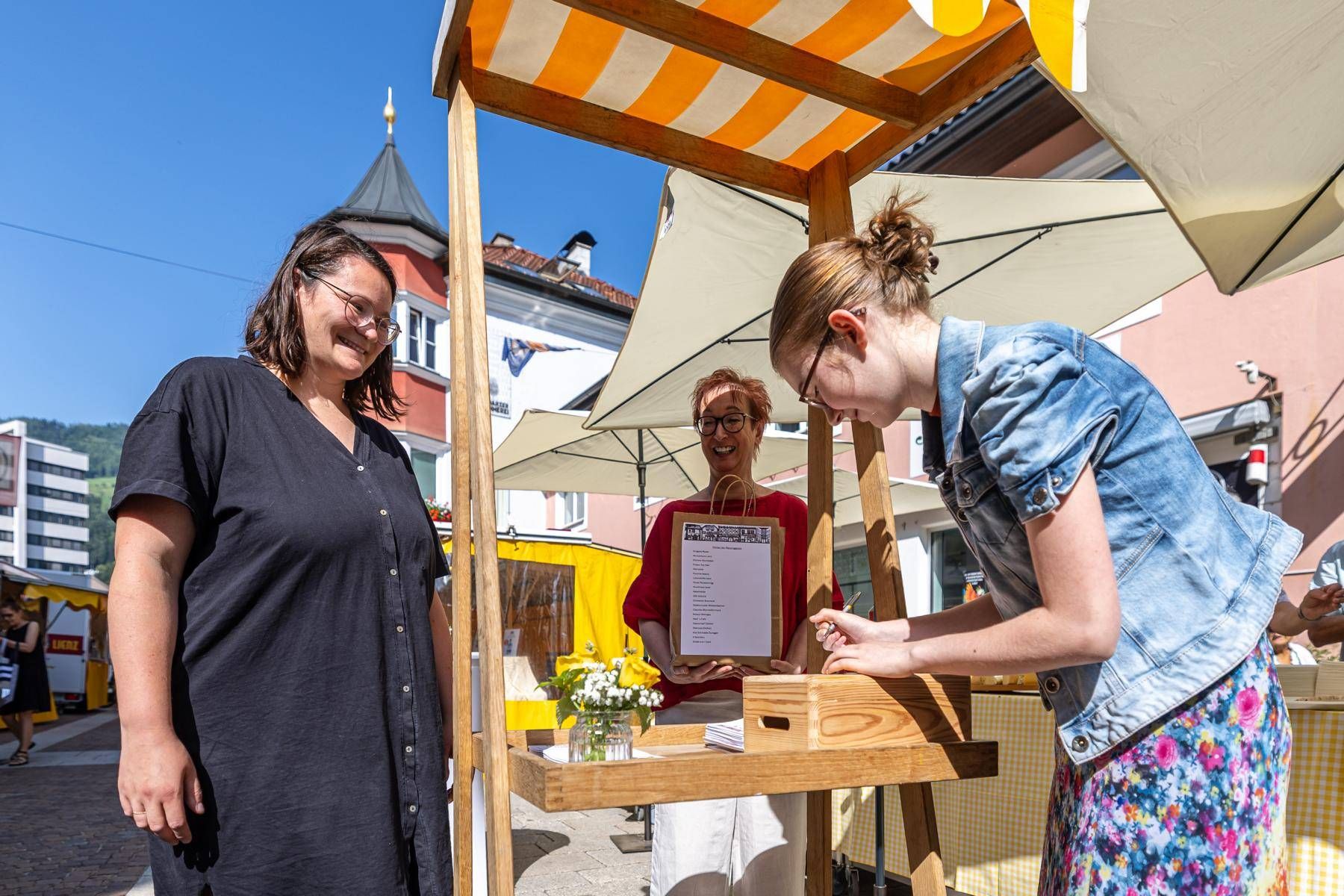 Theresa Kollnig (Verein Stadtmarkt und Zust&auml;ndig f&uuml;r den GenussLaden 24/7) bei der Registrierung f&uuml;r die Stammkundenkarte im GenussLaden 24/7 und Claudia Ambrosch (Obfrau Verein Messinggasse/Kreuzgasse) mit einem Goodybag als Gru&szlig; aus der Messinggasse  Foto: Expa Groder